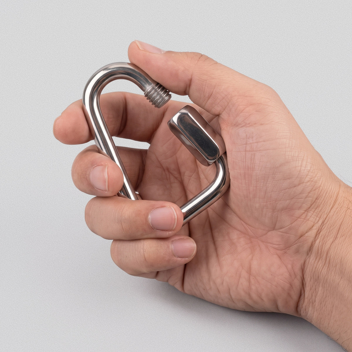 Hand holding a Power Band Carabiner, thumb on the screw gate.