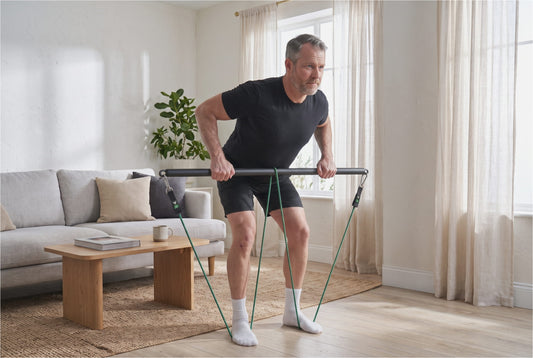 Man performing a bent-over row with stackable resistance bands and a bar at home