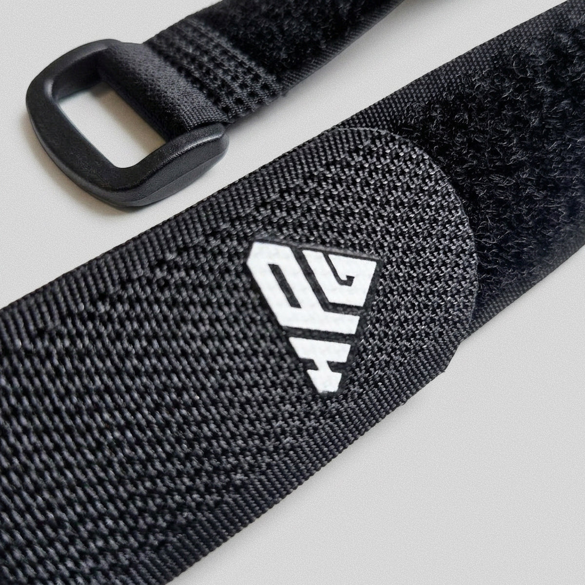 Buckle and hook-and-loop surface of the Clinch Band Storage Strap with the HomeProGym logo.