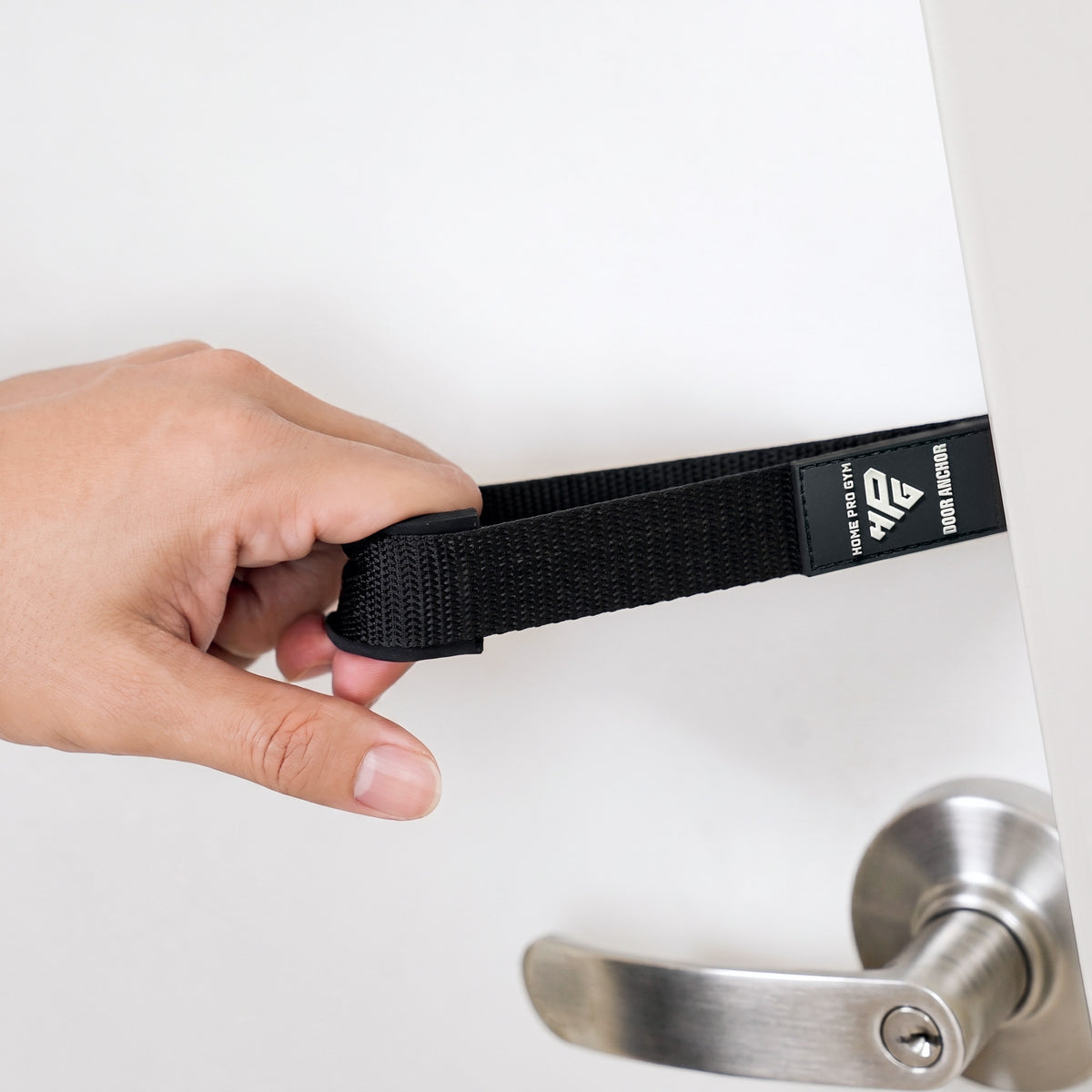 Hand holding the Door Anchor strap beside a door handle.