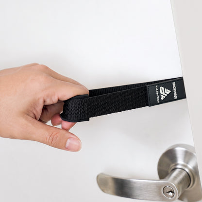 Hand holding the Door Anchor strap beside a door handle.