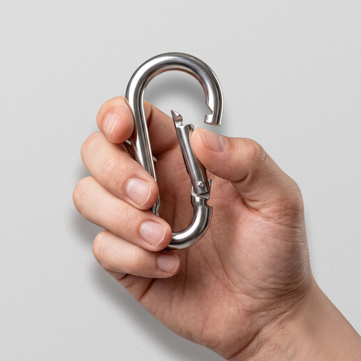 Hand holding a HomeProGym carabiner with the spring gate pressed open.