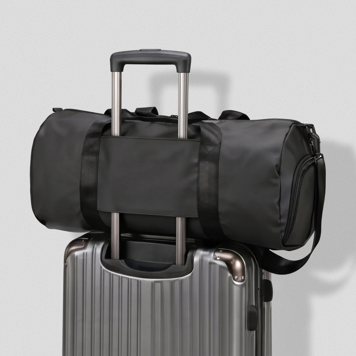 GymRoam 30L Duffle Bag slid over the handle of a rolling suitcase by its back sleeve.